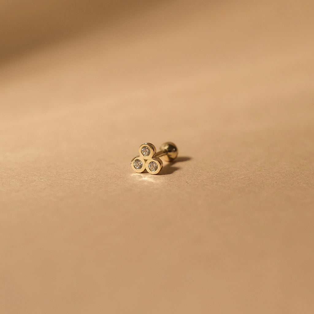 The MiJu Official solid gold sparkle ear piercing with three small cubic zirconia gemstones.